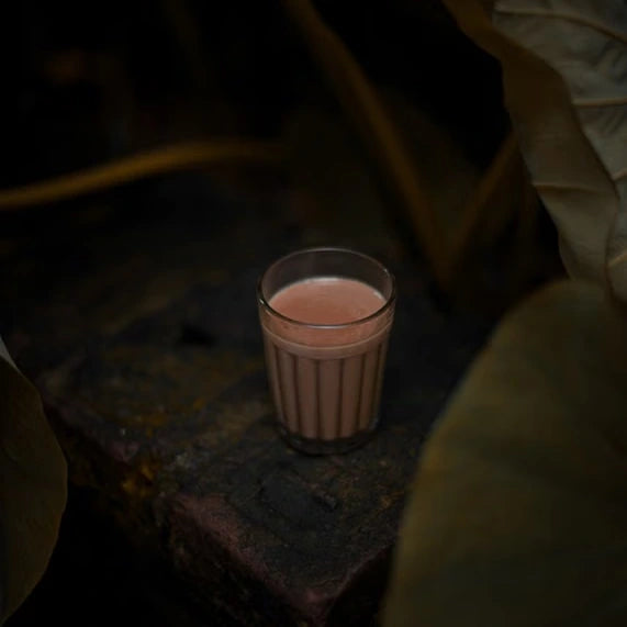 A glass of chai surrounded by dark foliage — illustrative serving or coffee study