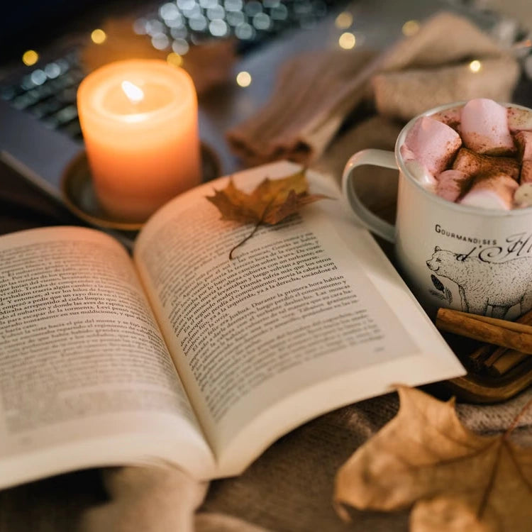Hot chocolate beside an open book and candle — illustrative serving or coffee study